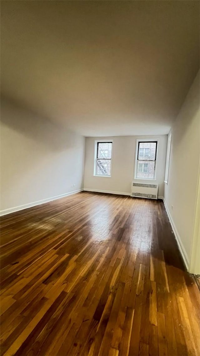 additional living space featuring dark hardwood / wood-style flooring and radiator heating unit