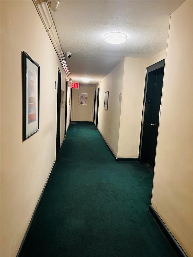 hall featuring dark carpet and a textured ceiling