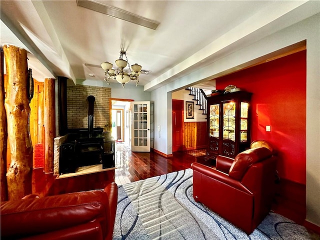 living room featuring a wood stove, french doors, a chandelier, and hardwood / wood-style flooring