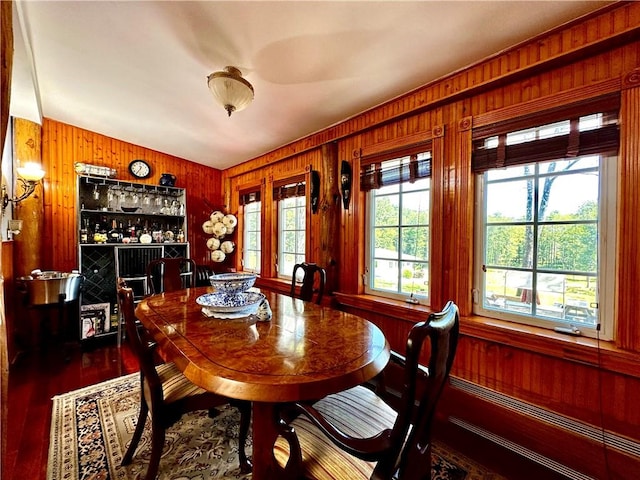 dining area featuring bar area, dark hardwood / wood-style floors, vaulted ceiling, and wooden walls