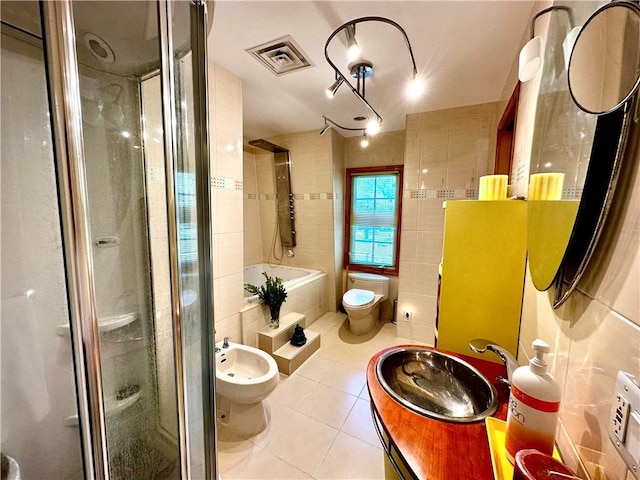 full bathroom with toilet, tile patterned floors, a bidet, and tile walls