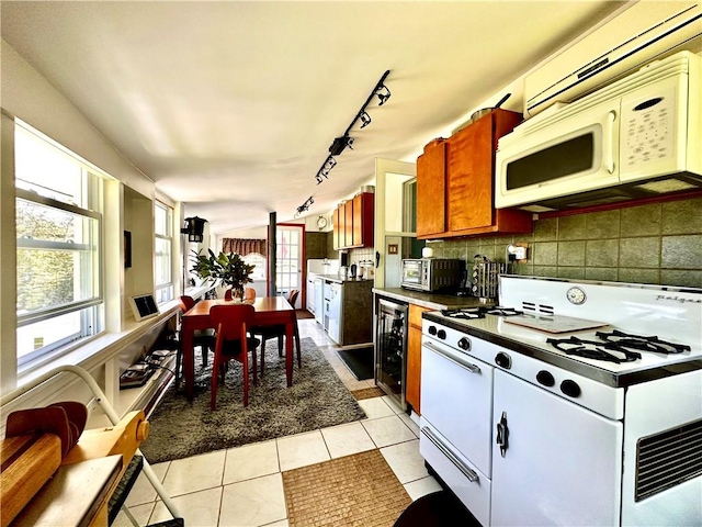 kitchen with light tile patterned floors, white appliances, beverage cooler, and backsplash