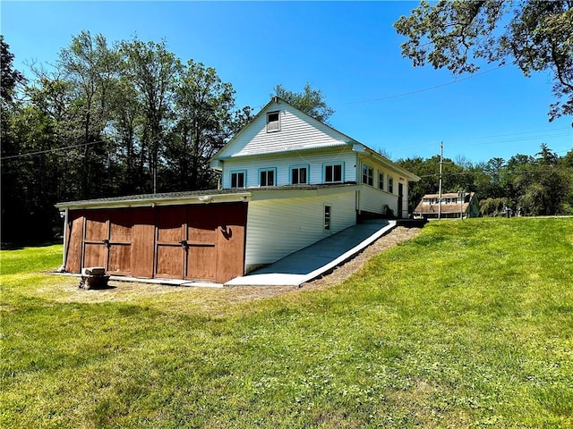 view of side of home featuring a lawn and a storage unit