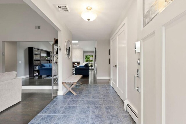 entryway featuring hardwood / wood-style floors, a large fireplace, and a baseboard radiator