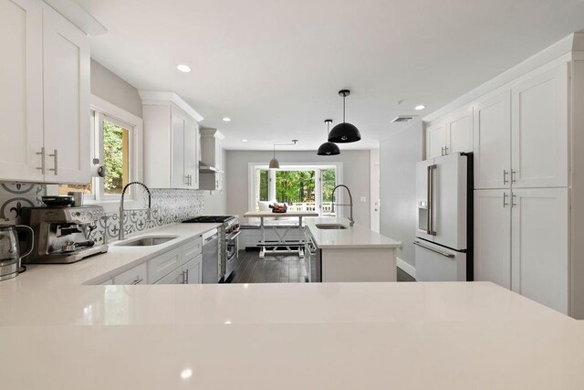 kitchen featuring high end appliances, sink, pendant lighting, dark hardwood / wood-style floors, and a kitchen island