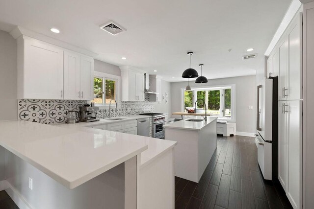 kitchen featuring kitchen peninsula, appliances with stainless steel finishes, a center island, and white cabinetry