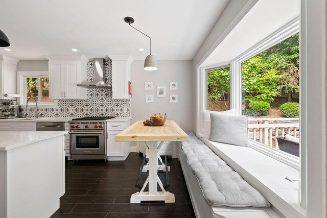 kitchen featuring designer stove, white cabinetry, wall chimney exhaust hood, and sink