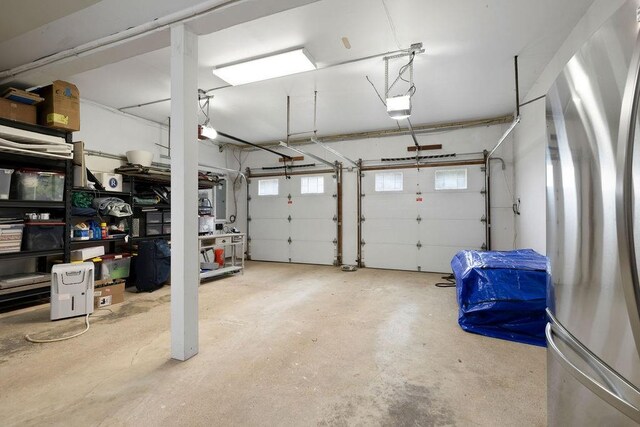 garage with a garage door opener and stainless steel refrigerator