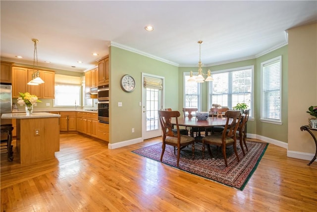 dining space with a healthy amount of sunlight, ornamental molding, and light hardwood / wood-style flooring