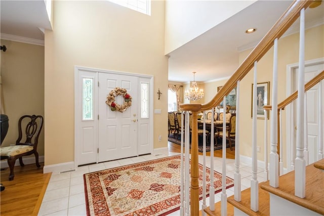 tiled foyer entrance featuring crown molding, plenty of natural light, and a chandelier