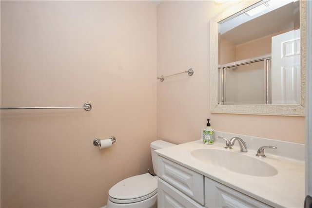 bathroom with vanity, toilet, and a shower with shower door