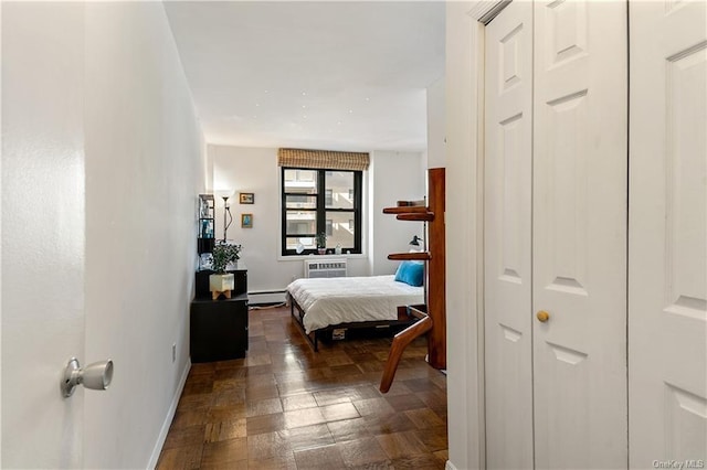 bedroom with a closet, a baseboard radiator, and a wall mounted air conditioner