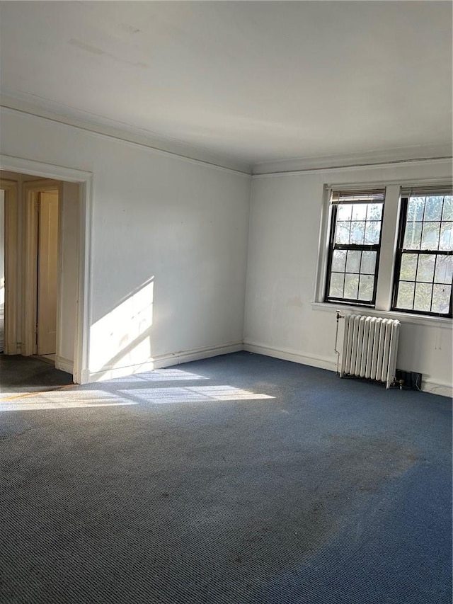 spare room featuring radiator heating unit and dark carpet