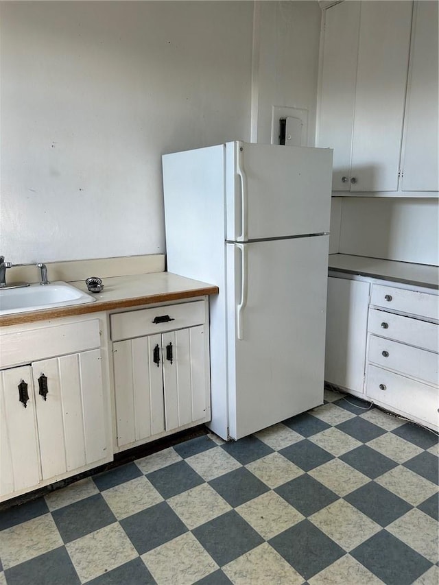 kitchen featuring white fridge, white cabinetry, and sink