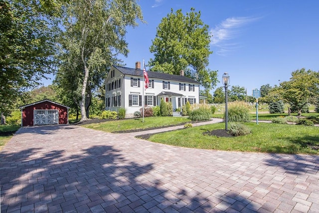 colonial inspired home featuring a garage, an outbuilding, and a front yard