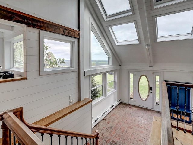 foyer featuring a healthy amount of sunlight, lofted ceiling with skylight, baseboard heating, and wooden walls