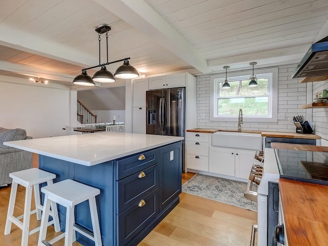 kitchen featuring blue cabinets, sink, stainless steel refrigerator with ice dispenser, light wood-type flooring, and white cabinetry