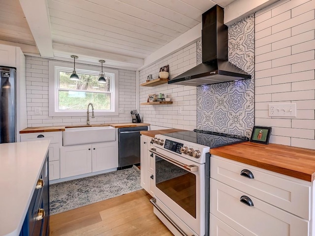 kitchen with wall chimney exhaust hood, light hardwood / wood-style floors, pendant lighting, electric range, and butcher block countertops