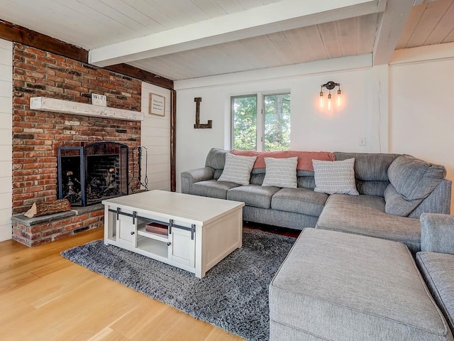 living room with beamed ceiling, hardwood / wood-style flooring, a brick fireplace, and wooden ceiling