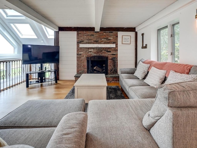 living room with a fireplace, beam ceiling, light hardwood / wood-style flooring, and a wealth of natural light