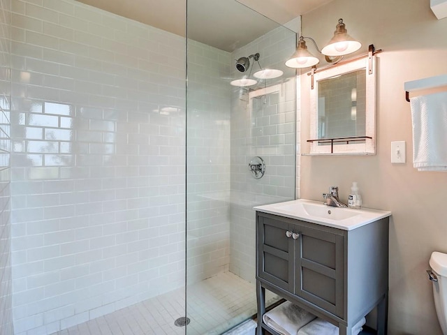 bathroom featuring a tile shower, vanity, and toilet