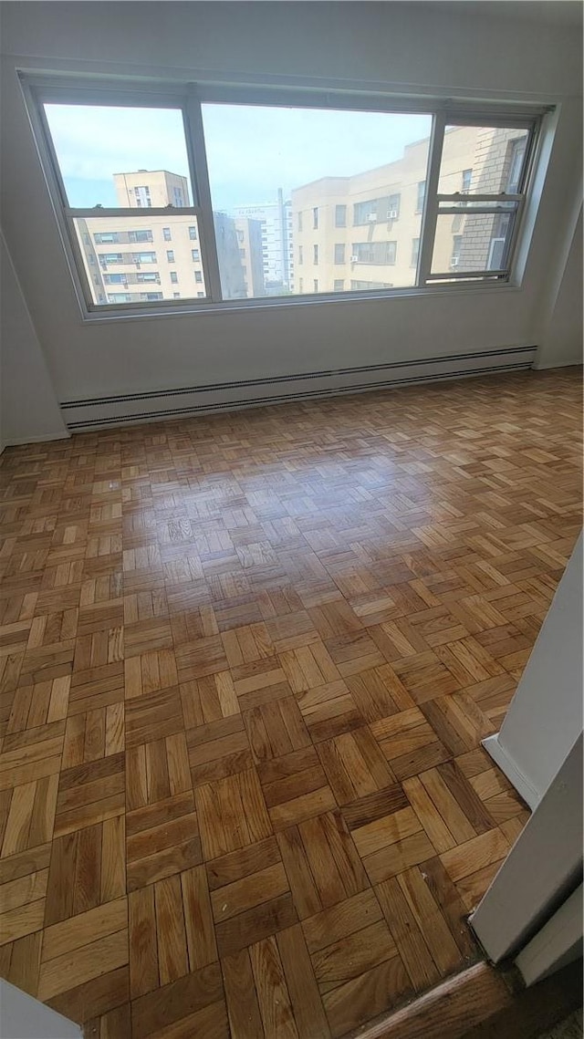 unfurnished room with parquet flooring and a baseboard radiator