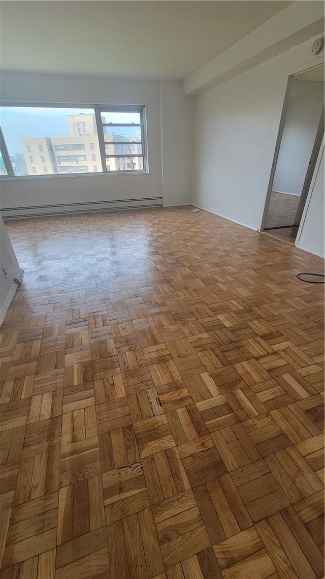 empty room with light parquet flooring and a baseboard heating unit