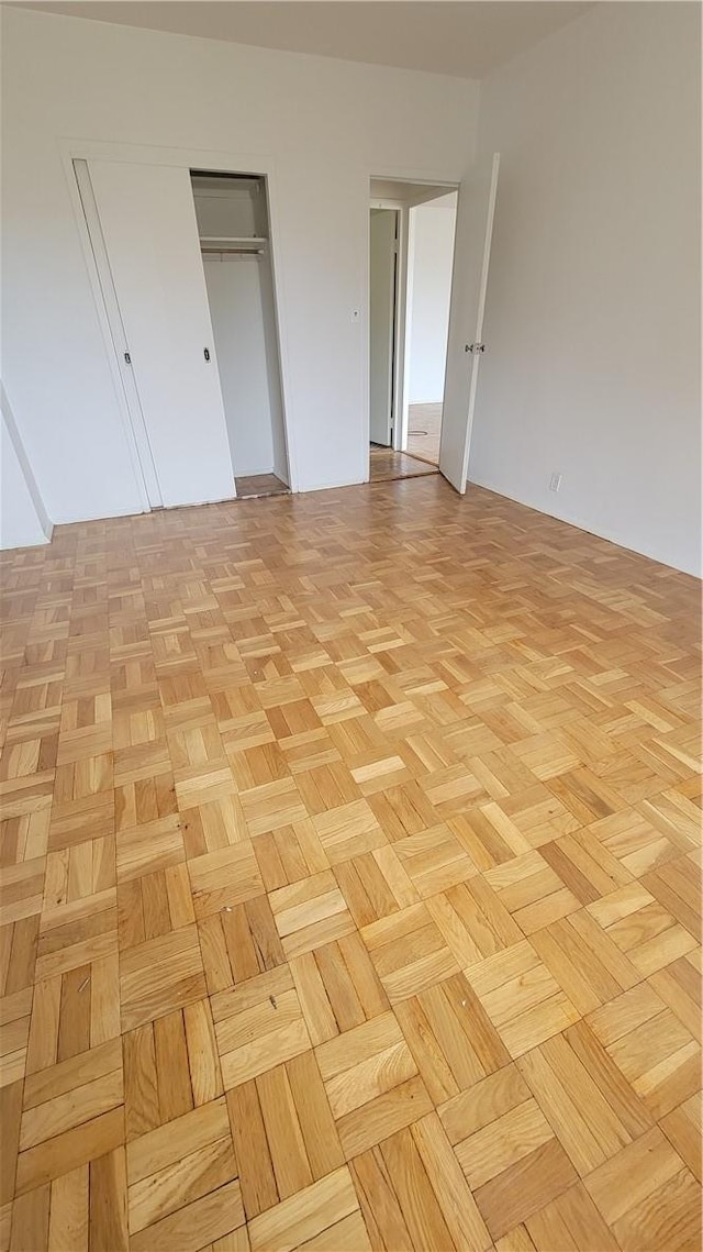 unfurnished bedroom featuring a closet and light parquet flooring