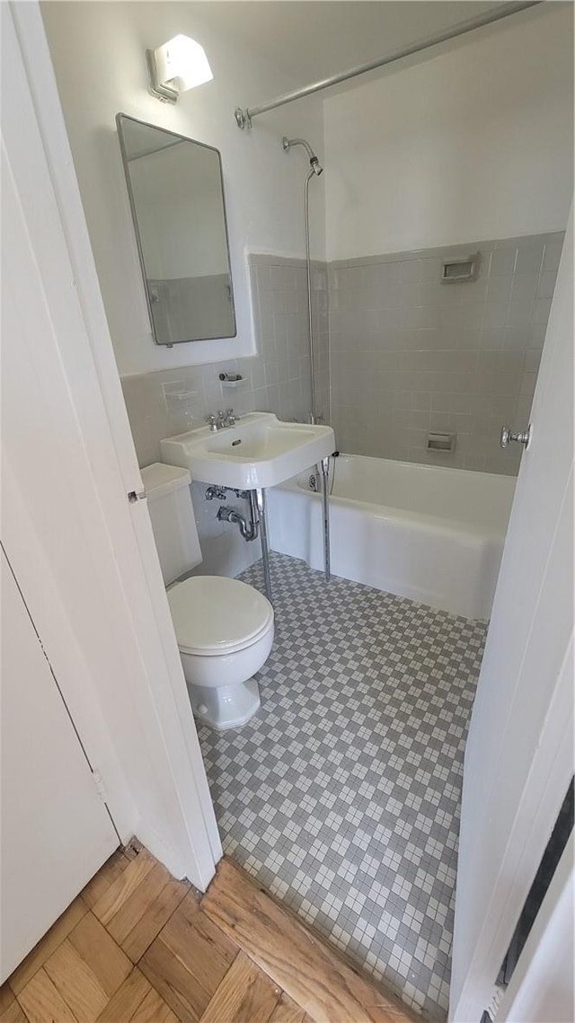 bathroom with toilet and tiled shower / bath