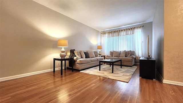living room with baseboards, wood finished floors, and vaulted ceiling