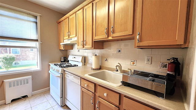kitchen with radiator heating unit, white dishwasher, range with gas cooktop, under cabinet range hood, and a sink