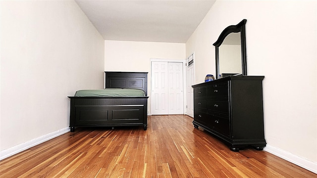 bedroom with light wood-type flooring, baseboards, and a closet