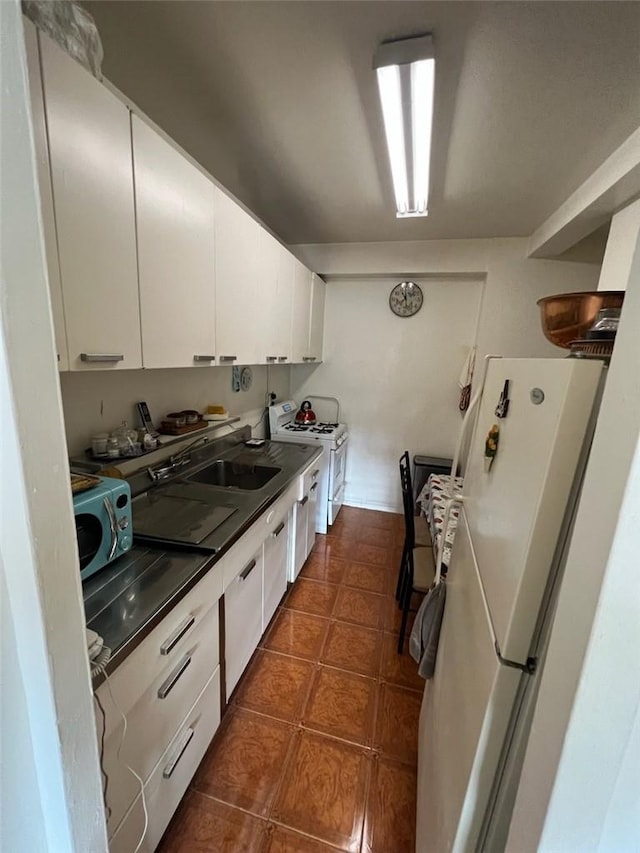 kitchen featuring white cabinetry, white appliances, sink, and dark tile patterned floors