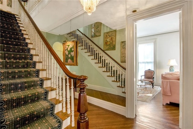 stairway featuring a chandelier and crown molding