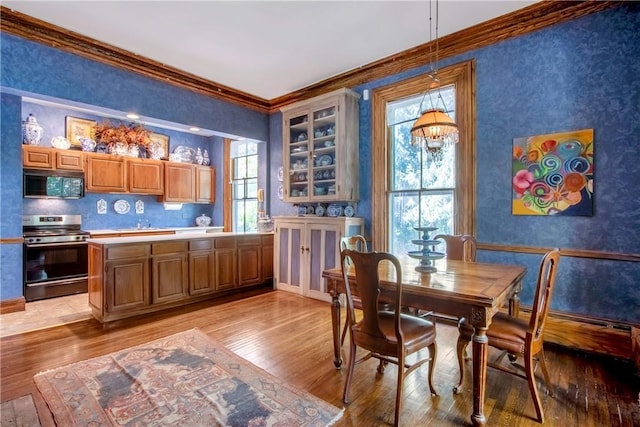 dining area featuring light hardwood / wood-style flooring, a wealth of natural light, ornamental molding, and a notable chandelier