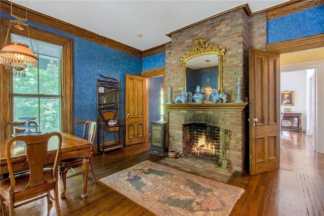 sitting room with dark hardwood / wood-style flooring, crown molding, a fireplace, and a notable chandelier