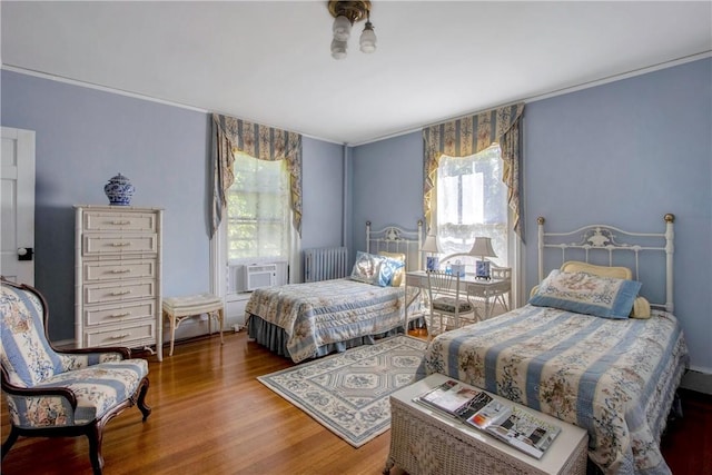 bedroom featuring radiator heating unit, cooling unit, and hardwood / wood-style flooring