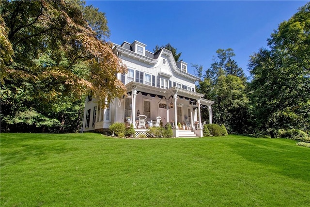 back of house featuring covered porch and a yard