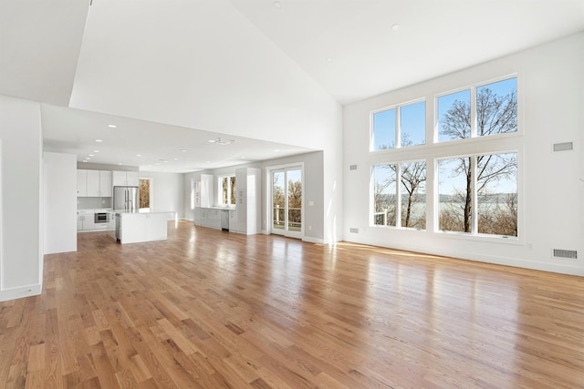 201 Tweed Blvd, Piermont, NY 10960 - unfurnished living room featuring a towering ceiling, light wood-type flooring, and recessed lighting