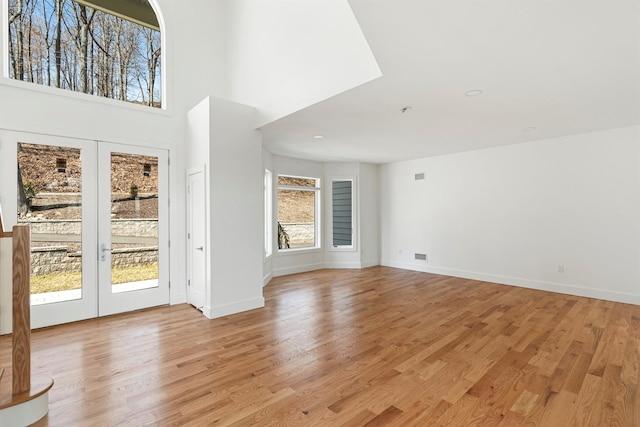 201 Tweed Blvd, Piermont, NY 10960 - unfurnished living room featuring light wood finished floors, a high ceiling, and french doors