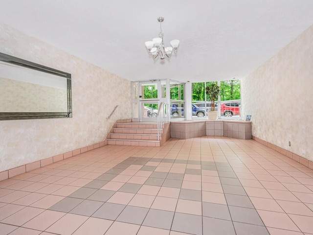 tiled empty room featuring a notable chandelier, stairway, and wallpapered walls