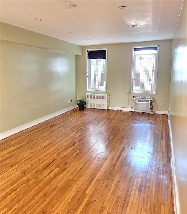 unfurnished room featuring an AC wall unit, radiator heating unit, and wood-type flooring