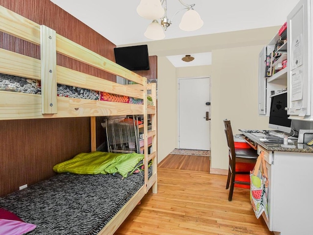 bedroom with light hardwood / wood-style floors and an inviting chandelier