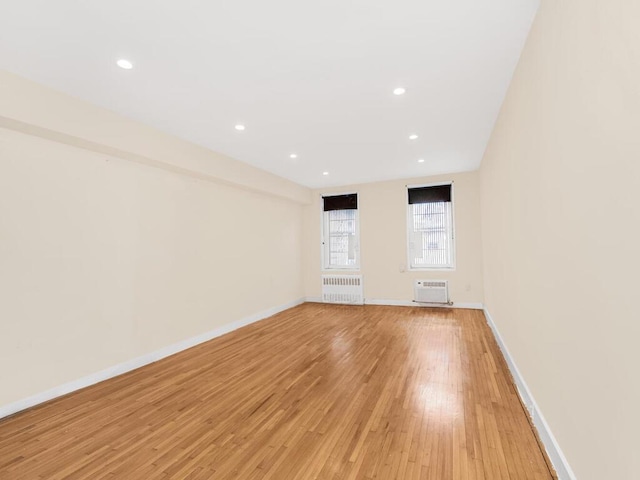 unfurnished living room featuring light wood-type flooring, radiator heating unit, baseboards, and recessed lighting