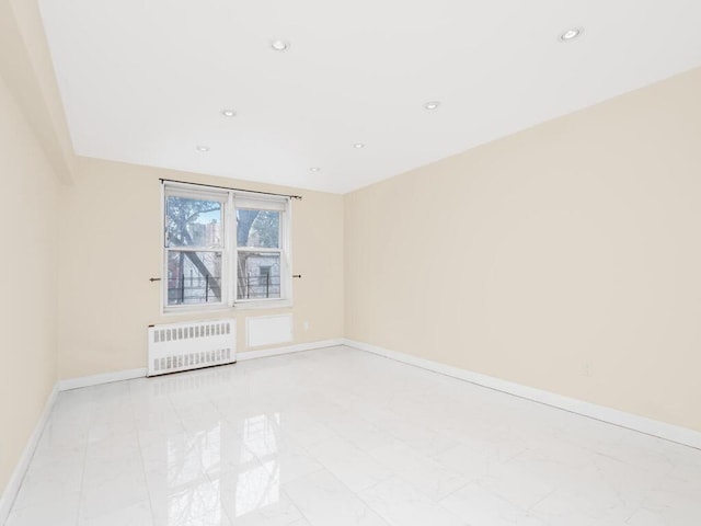 spare room with radiator heating unit, baseboards, and recessed lighting