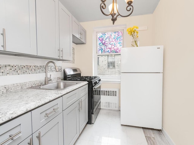 kitchen with a sink, freestanding refrigerator, radiator, gas stove, and an inviting chandelier