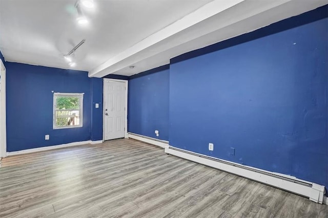 empty room with track lighting, a baseboard radiator, wood finished floors, and baseboards