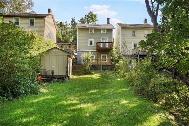 rear view of property featuring an outbuilding, a yard, a deck, and a shed