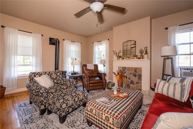 living room featuring hardwood / wood-style floors, plenty of natural light, ceiling fan, and a wood stove