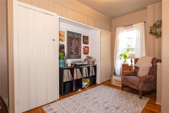 living area with wood-type flooring and ornamental molding